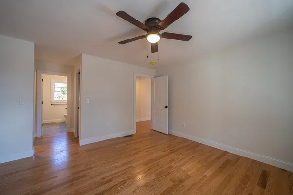an empty room with wooden floor and a ceiling fan