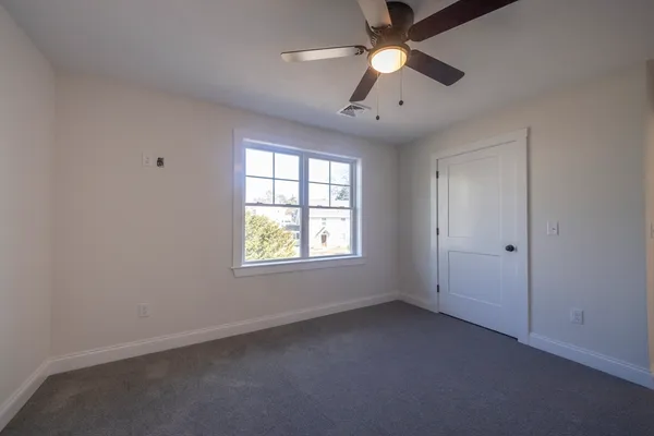 an empty room with a window and a fan