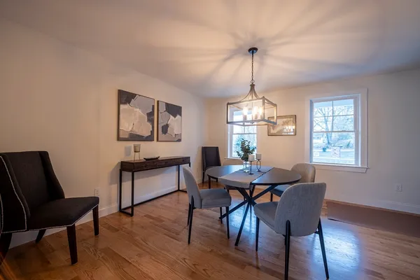 a dining room with wooden floor a chandelier a wooden table and chairs