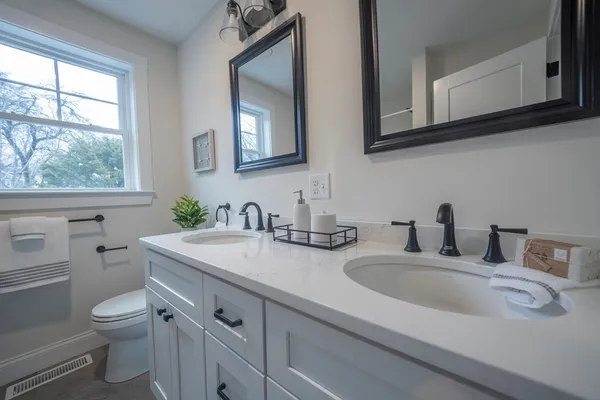 a bathroom with double vanity sink a toilet and a window