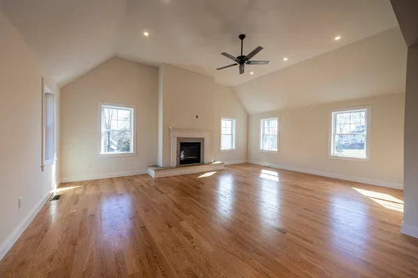 an empty room with wooden floor a ceiling fan and windows