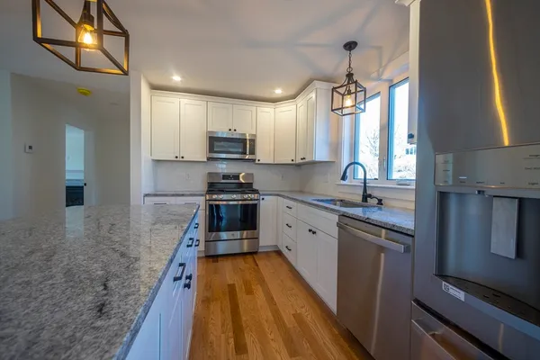 a kitchen with kitchen island granite countertop a sink appliances cabinets and a counter top space