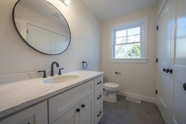 a bathroom with a granite countertop toilet a sink and a mirror