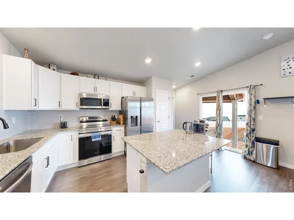 a kitchen with stainless steel appliances granite countertop a sink refrigerator and cabinets