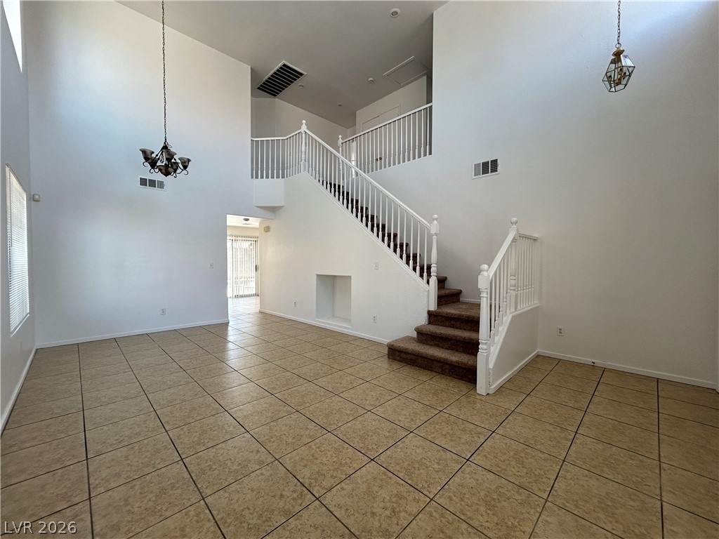 7373 Randel Jean Way Las Vegas, NV 89113 - Photo 2 of 14 Tiled flooring and soaring high ceilings frame a central staircase in this open entryway.