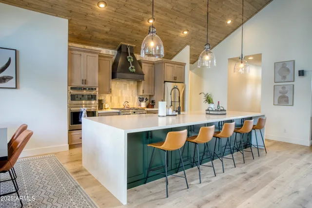 a kitchen with kitchen island granite countertop a table chairs sink and cabinets