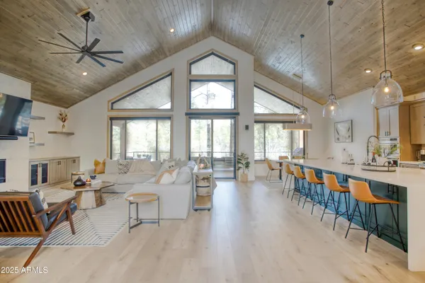a living room with furniture a chandelier fan and a large window