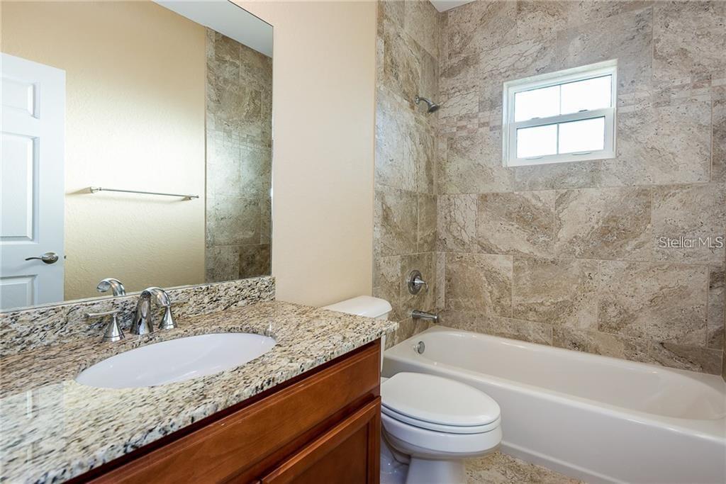 3948 San Rocco Drive, Unit 112 Punta Gorda, FL 33950 - Photo 16 of 18 a bathroom with a granite countertop toilet a sink and a bathtub