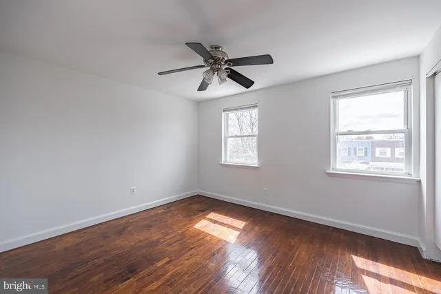 a view of empty room with wooden floor and fan