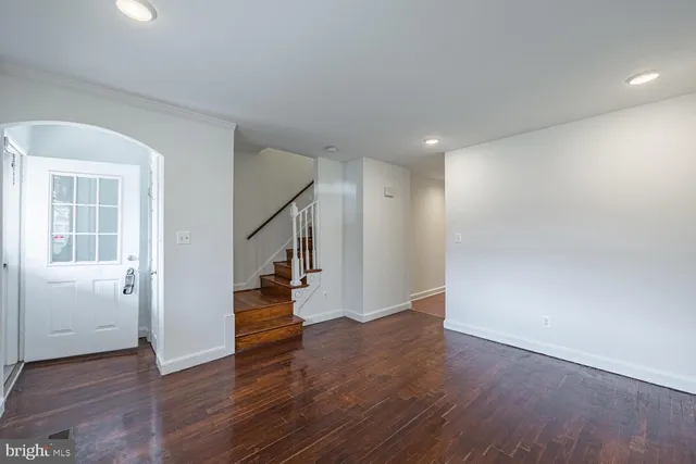 a view of an empty room with wooden floor and stairs