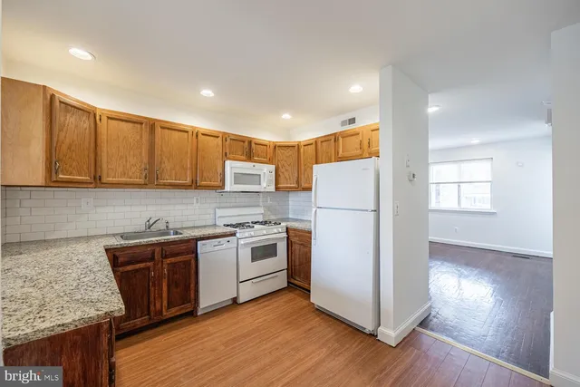 a kitchen with a refrigerator a sink and wooden floor
