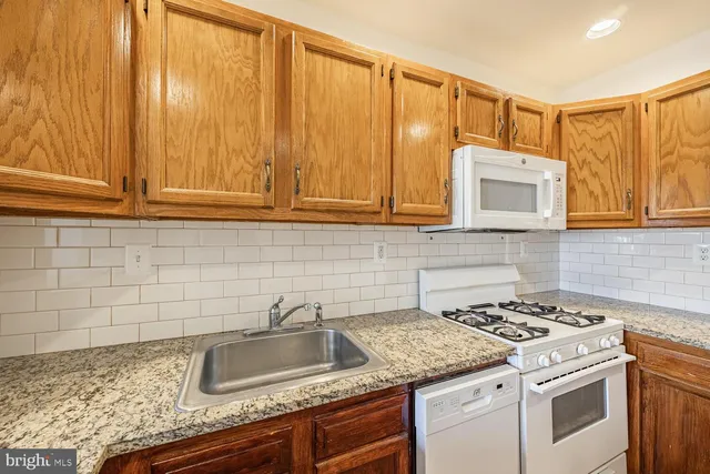 a kitchen with granite countertop a sink stove and cabinets