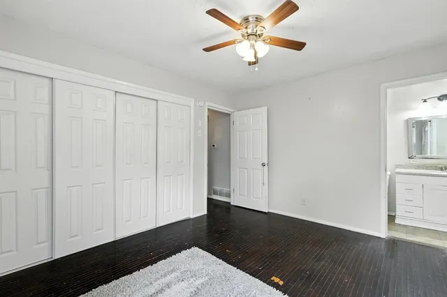 an empty room with wooden floor closet and windows