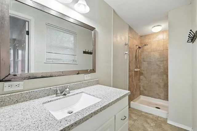 a bathroom with a granite countertop sink mirror and shower