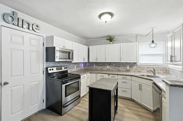 a kitchen with stainless steel appliances granite countertop a stove a sink and a microwave