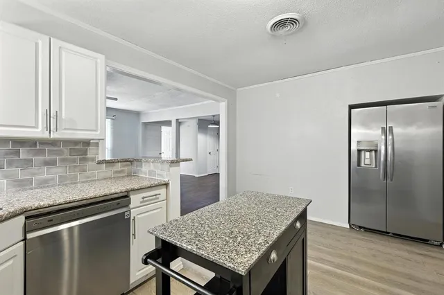 a kitchen with granite countertop a sink cabinets and stainless steel appliances