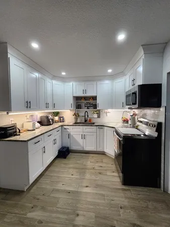 a large kitchen with kitchen island granite countertop a sink dishwasher a stove and a refrigerator with wooden floor