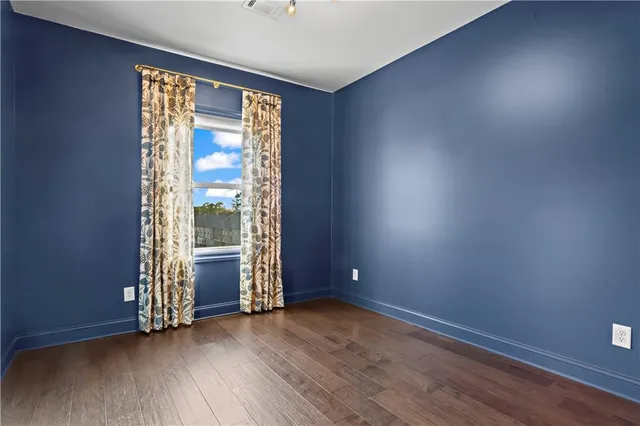 an empty room with wooden floor and windows with curtains