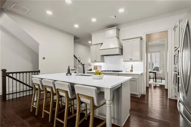 a kitchen with stainless steel appliances kitchen island granite countertop a table chairs sink and cabinets