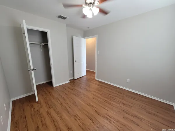 an empty room with wooden floor and a ceiling fan
