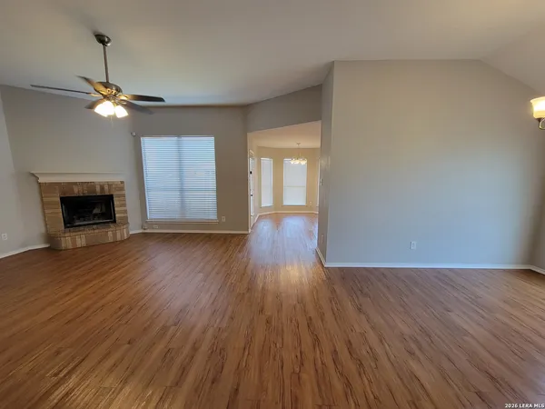 an empty room with wooden floor fireplace and windows