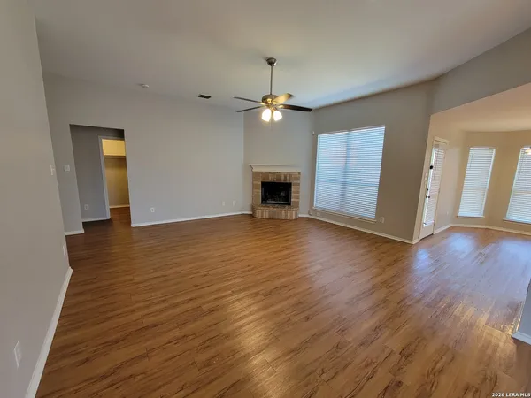 a view of a livingroom with wooden floor a ceiling fan and a kitchen