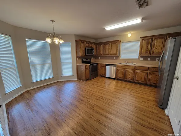 a open kitchen with stainless steel appliances granite countertop a refrigerator a stove top oven a sink dishwasher and wooden floor