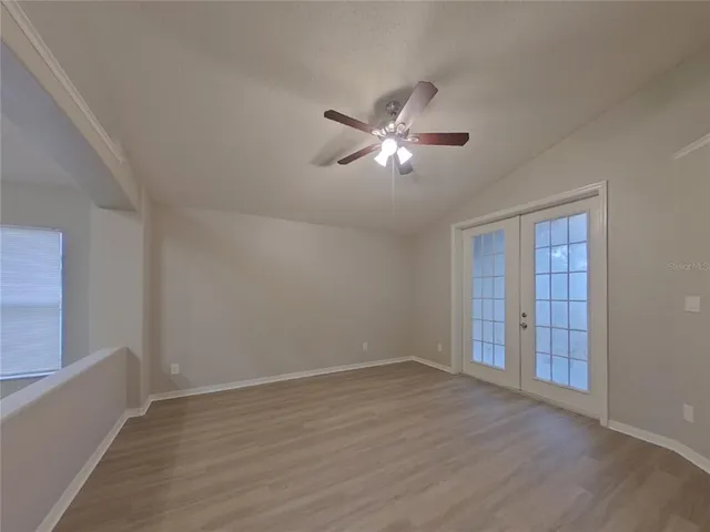 a view of an empty room with a window and wooden floor