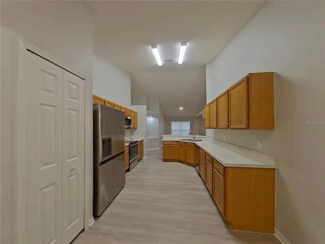 a view of a kitchen with stainless steel appliances wooden cabinets and a large window