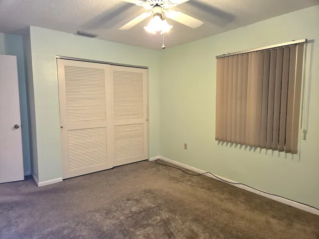an empty room with a fan & a window