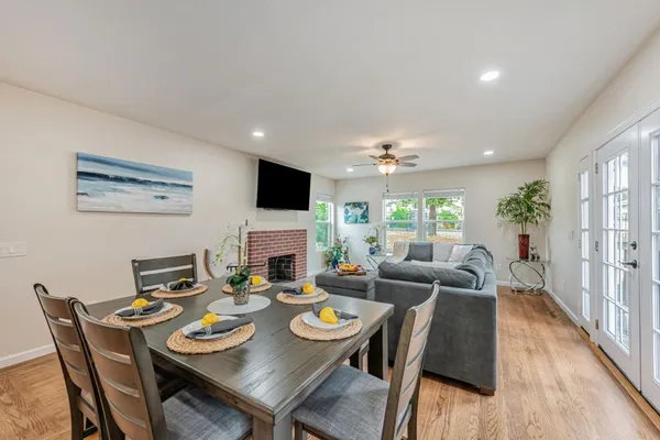 a kitchen with stainless steel appliances granite countertop a refrigerator a stove top oven a sink dishwasher and a dining table with wooden floor
