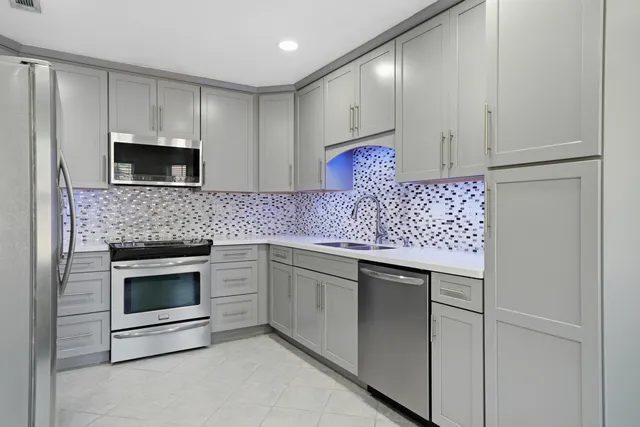 a kitchen with granite countertop white cabinets stainless steel appliances and a counter space