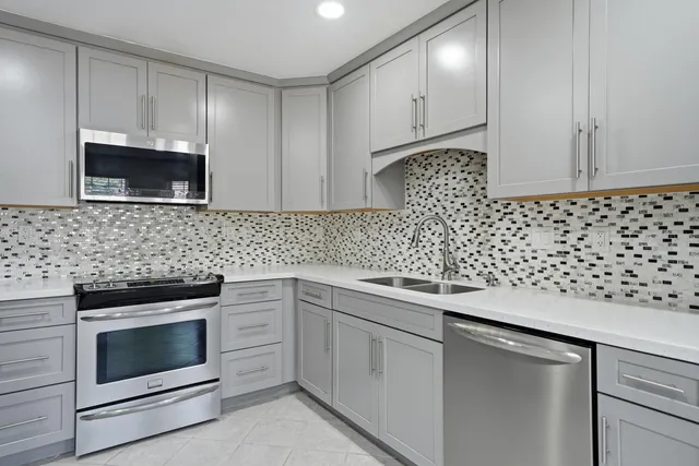 a kitchen with granite countertop white cabinets and stainless steel appliances