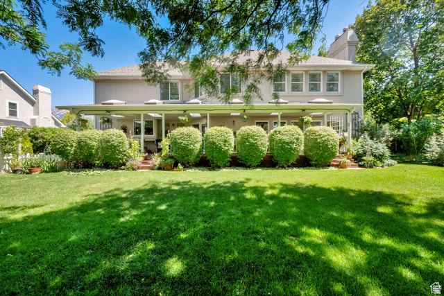 7740 Keswick Road Sandy, UT 84093 - Photo 59 of 74 Expansive backyard featuring a manicured lawn, mature trees, and a covered patio with architectural columns