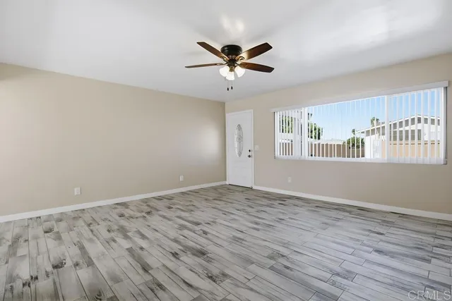a view of an empty room with window and wooden floor