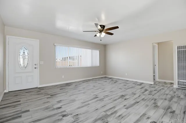 a view of an empty room with window and wooden floor