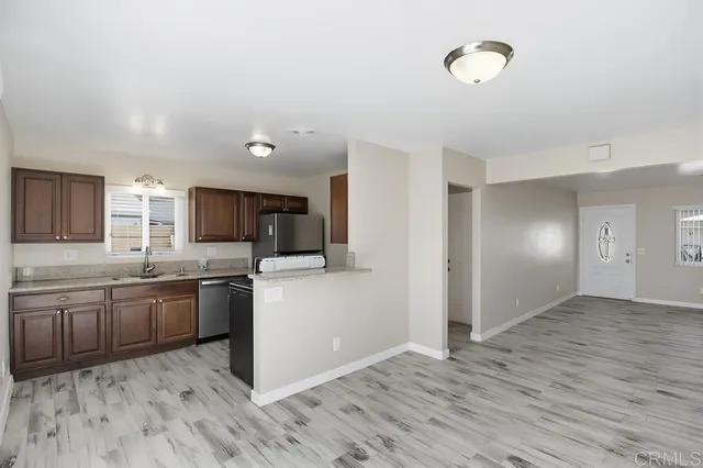 a kitchen with stainless steel appliances granite countertop a stove top oven a sink dishwasher and a refrigerator with wooden floor