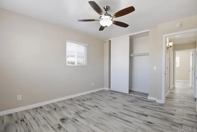 an empty room with wooden floor and a ceiling fan