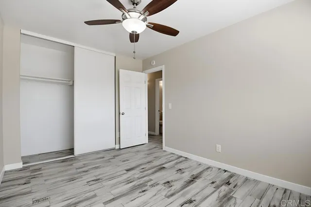 an empty room with wooden floor a ceiling fan and closet