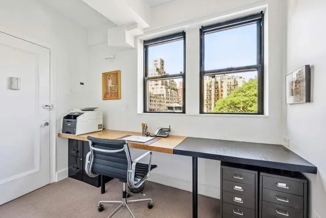 a view of a workspace with furniture and a window