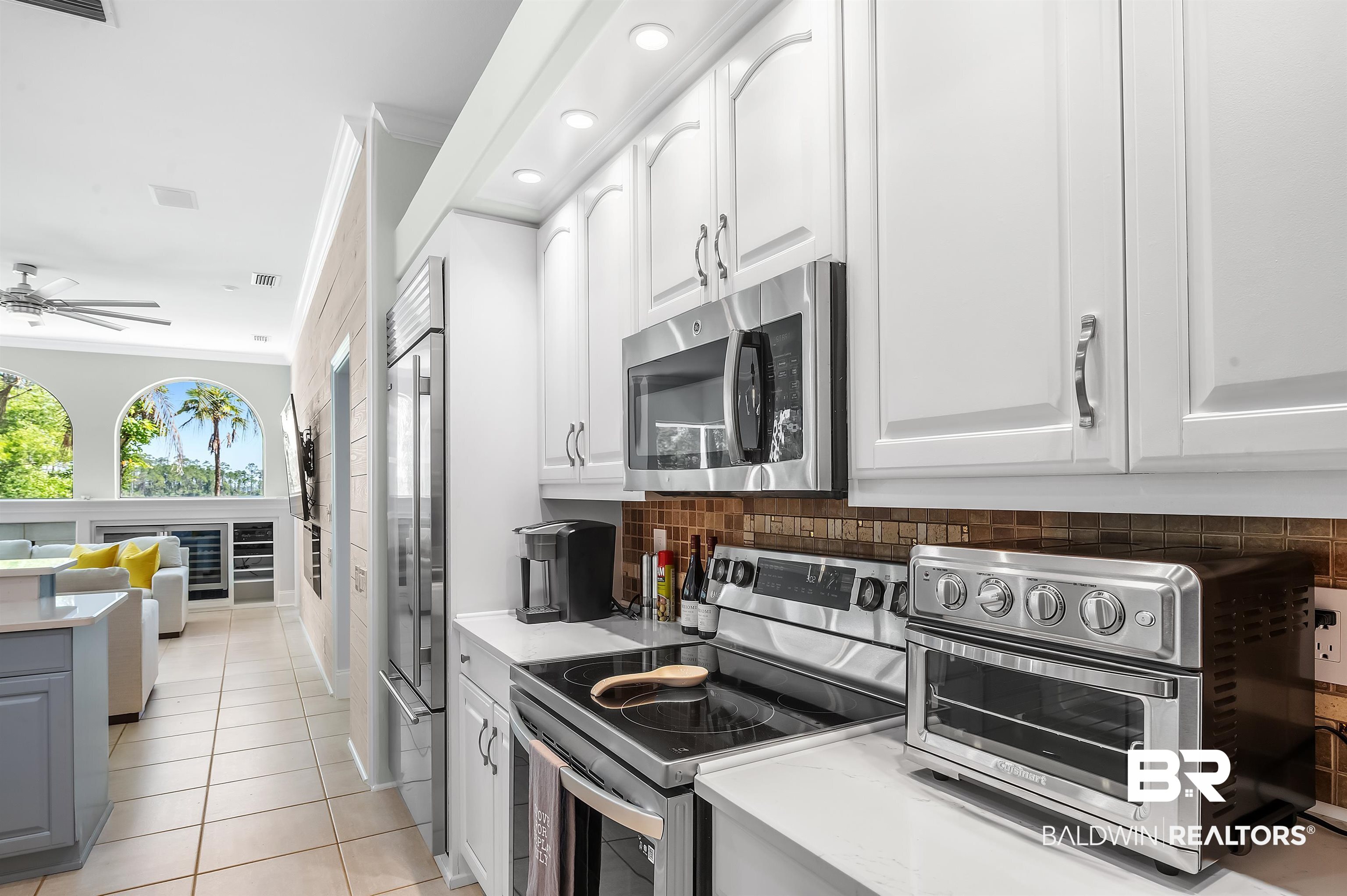 8160 Bay View Drive Foley, AL 36535 - Photo 18 of 43 Kitchen featuring appliances with stainless steel finishes, tasteful backsplash, light countertops, white cabinetry, and crown molding