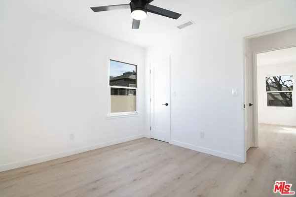 an empty room with a window and ceiling fan