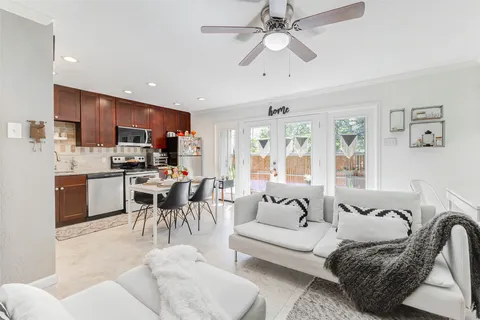 a living room with furniture kitchen view and a chandelier