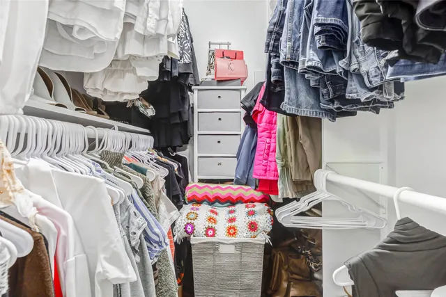 a view of walk in closet with clothes and shoes