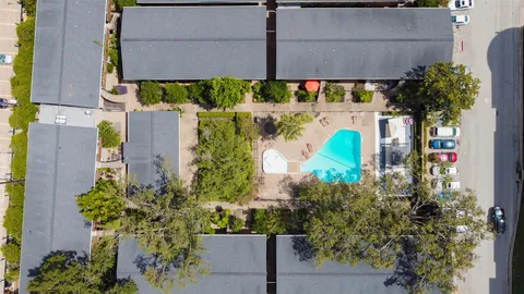 an aerial view of a swimming pool with outdoor seating and yard