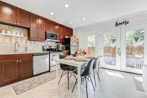 a kitchen with stainless steel appliances granite countertop a stove a sink dishwasher a microwave oven and a dining table with wooden cabinet