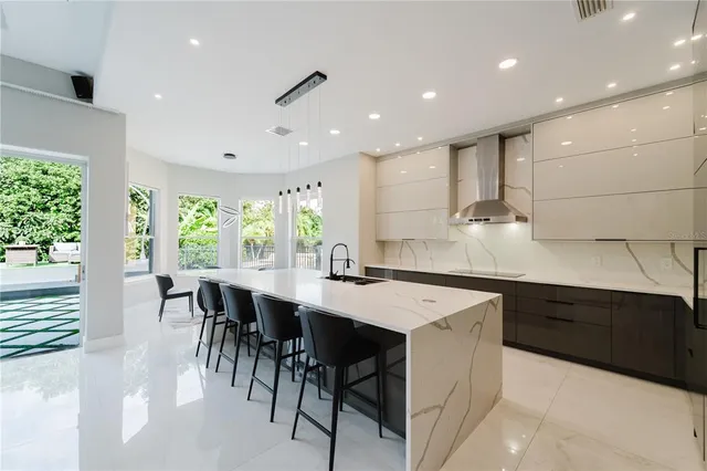 a kitchen with kitchen island a dining table chairs and white cabinets