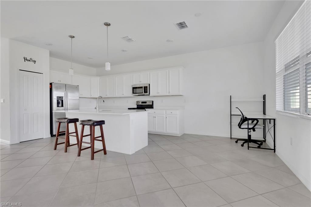 2553 Kona Way Naples, FL 34120 - Photo 6 of 27 a kitchen with white cabinets and stainless steel appliances