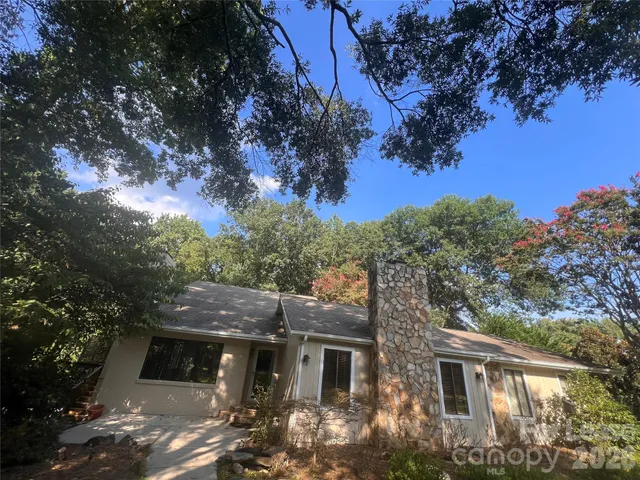 a front view of house with yard and trees in the background
