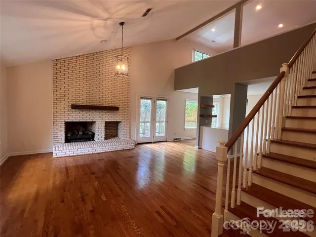 a view of an empty room with wooden floor fireplace and a window